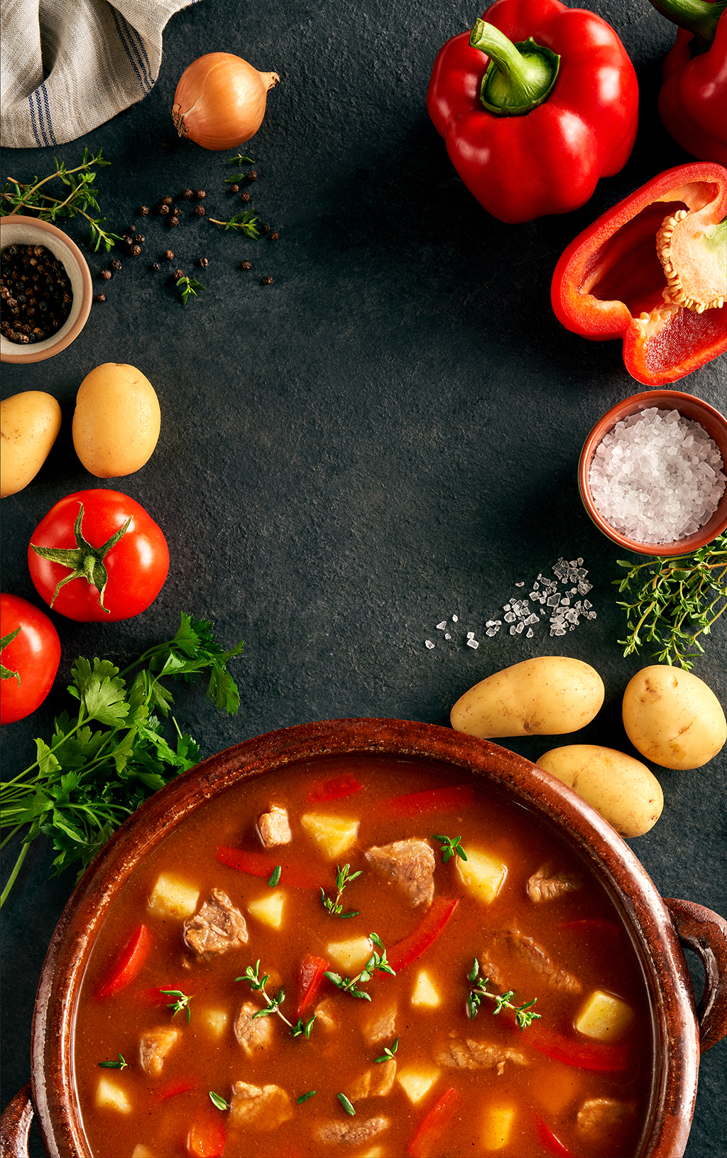 Zupa gulaszowa w rustykalnym garnku na ciemnym tle