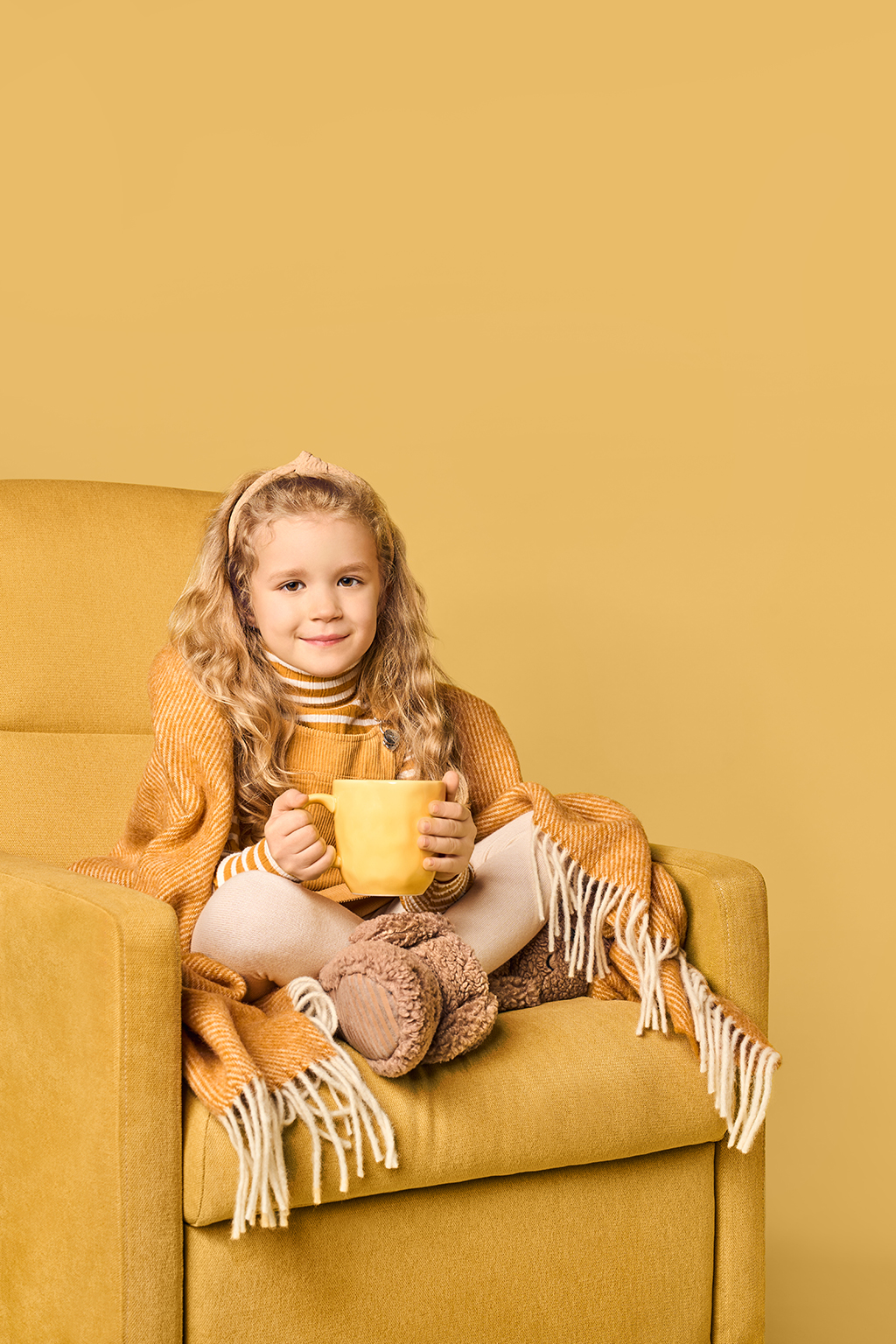 a girl with a mug sitting on armchair